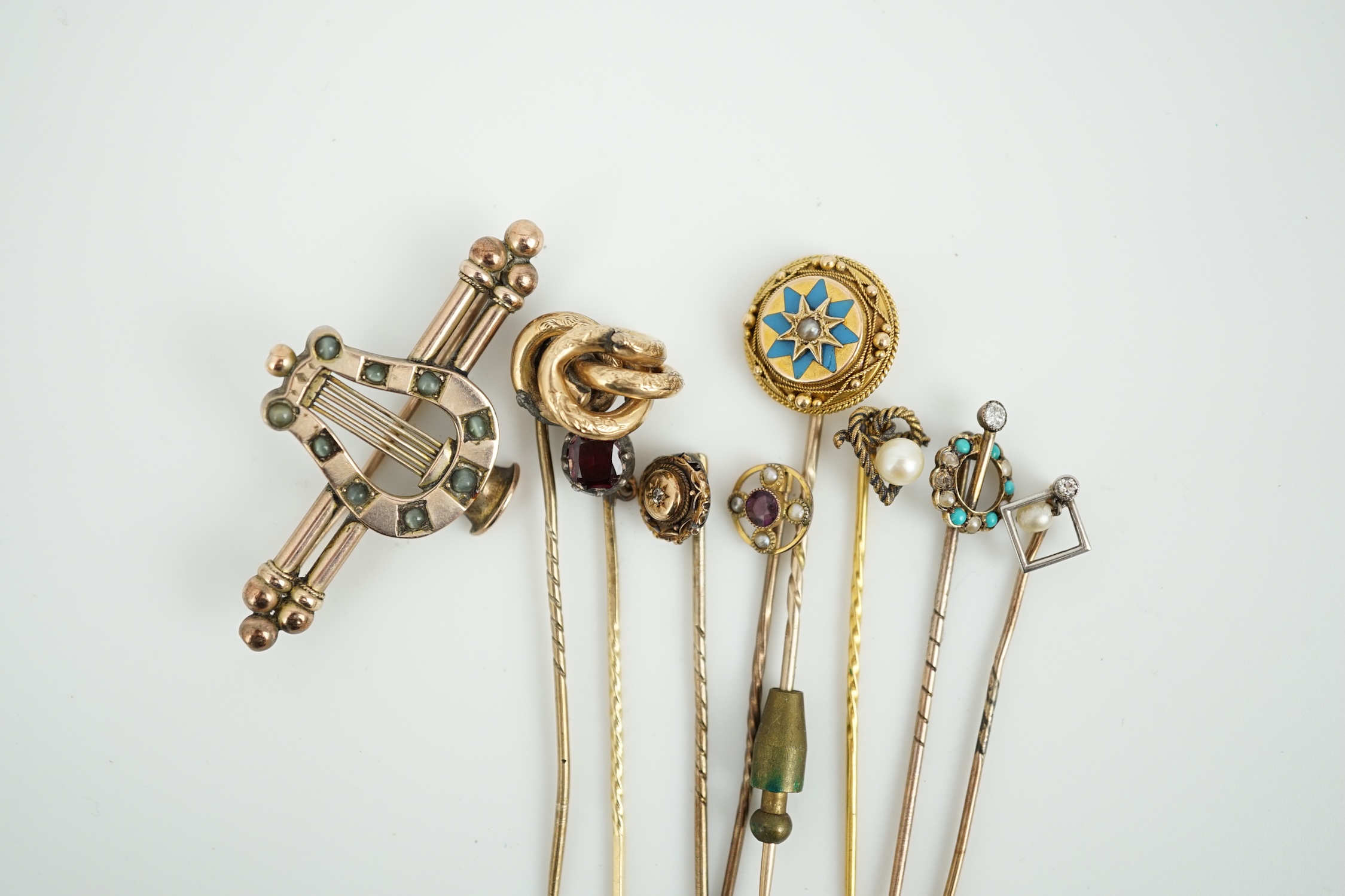 A Victorian yellow metal and cat's eye chrysoberyl set lyre bar brooch, 51mm and eight assorted gem set yellow metal stick pins including enamel and diamond set.